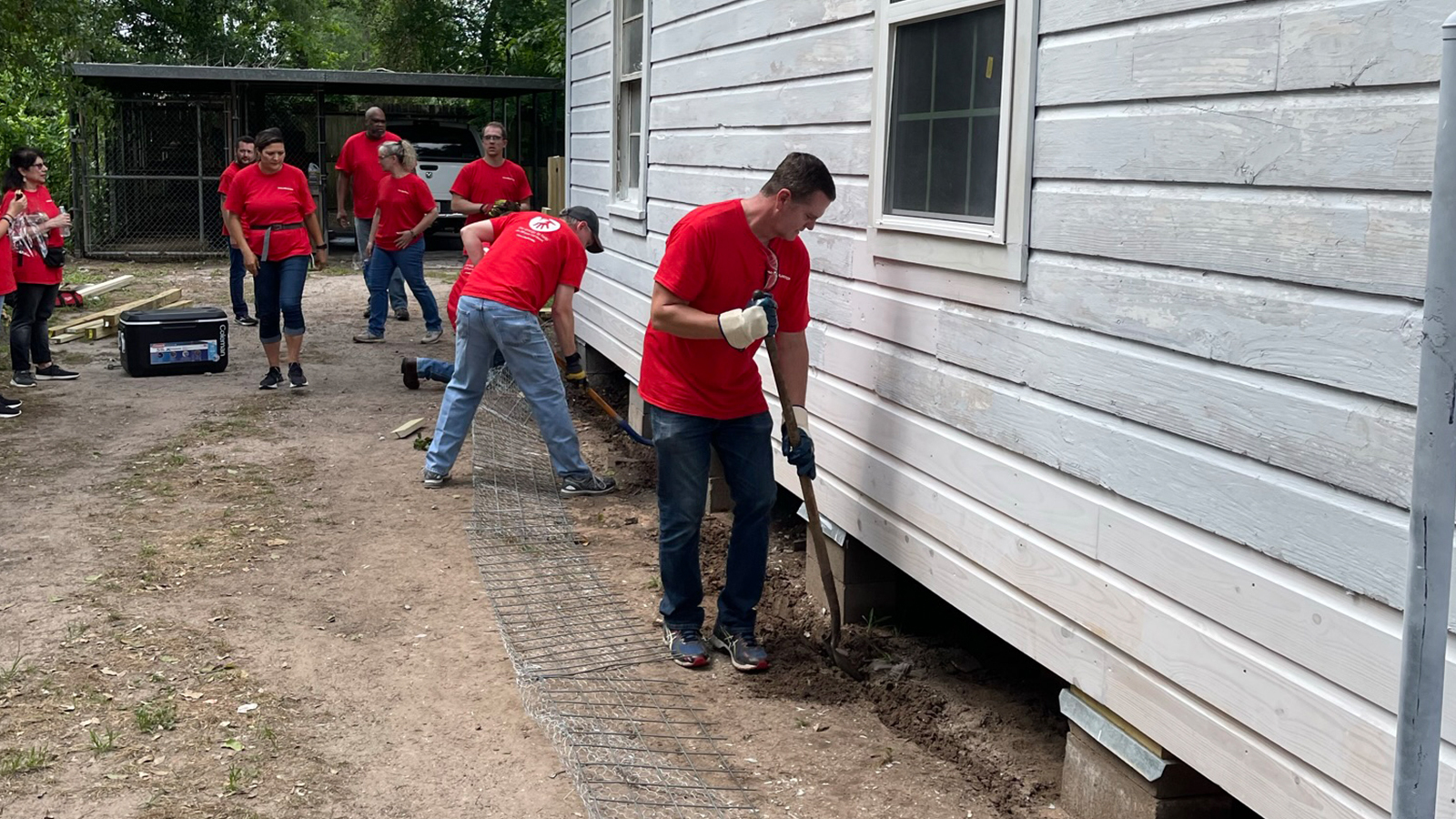 Halliburton volunteers helping to dig a trench around a house.