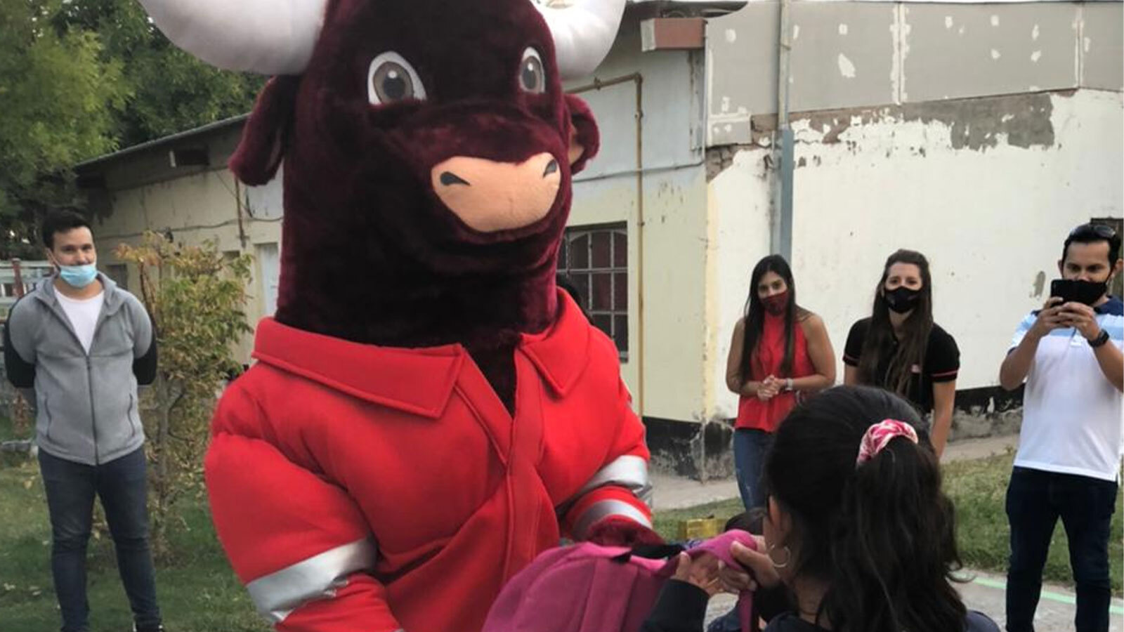 "Halli-bull", the Halliburton Argentina mascot, distributing backpacks to students