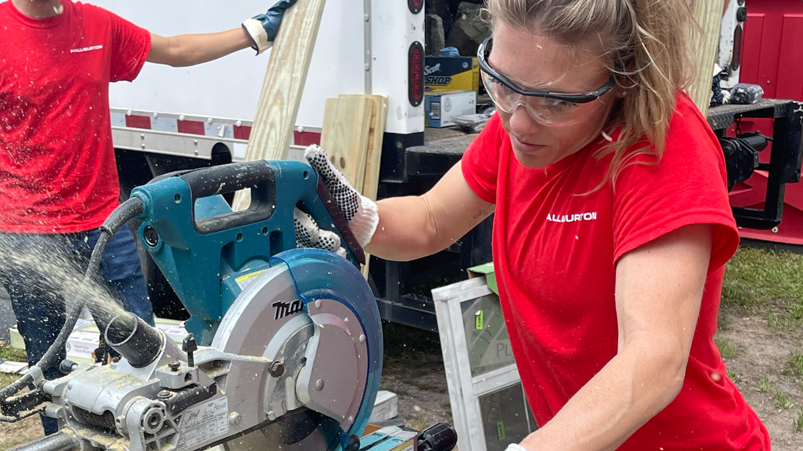 Halliburton volunteer cutting wood using a miter saw.