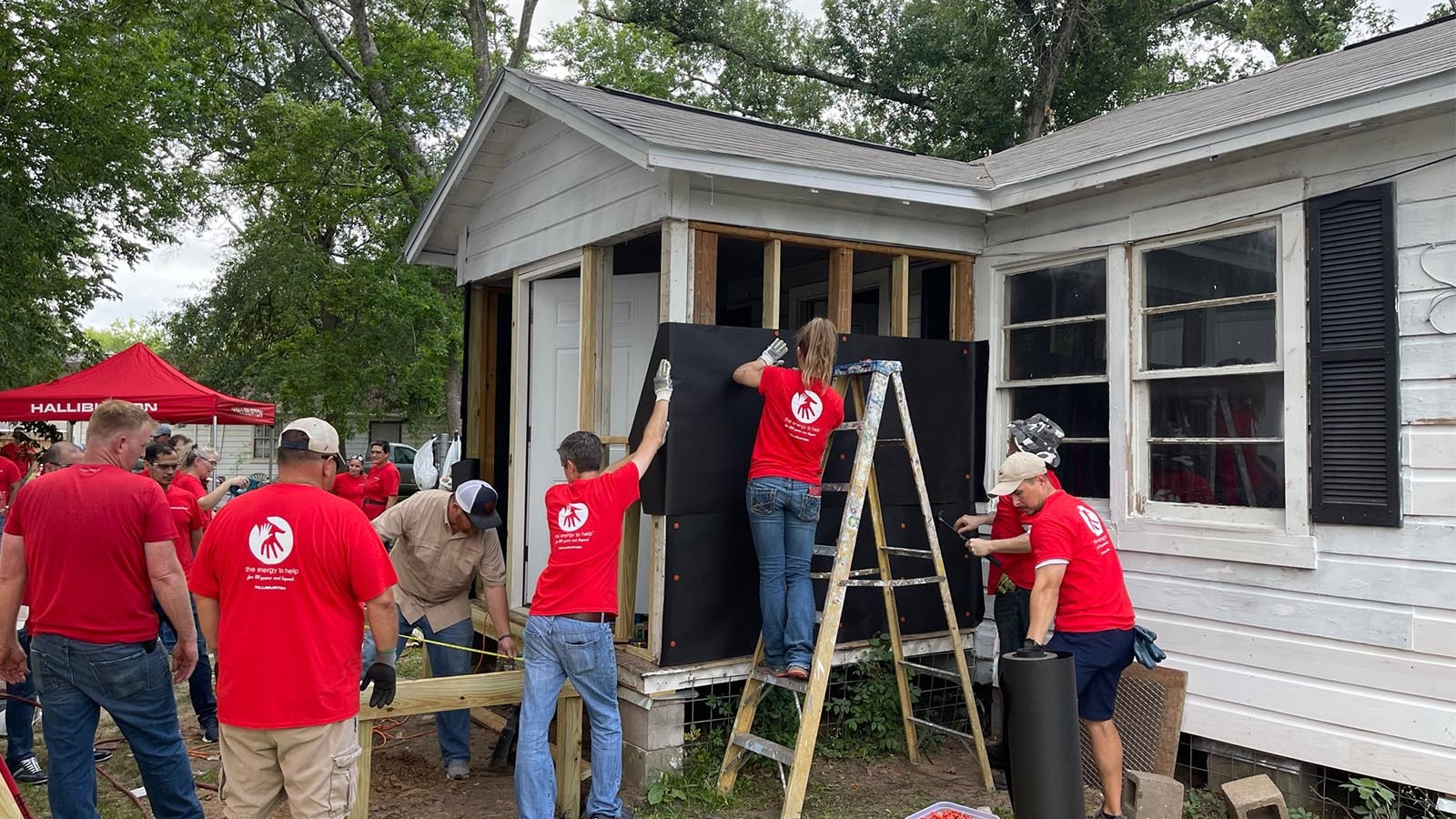 Halliburton volunteers working on repairing the outside of a house.