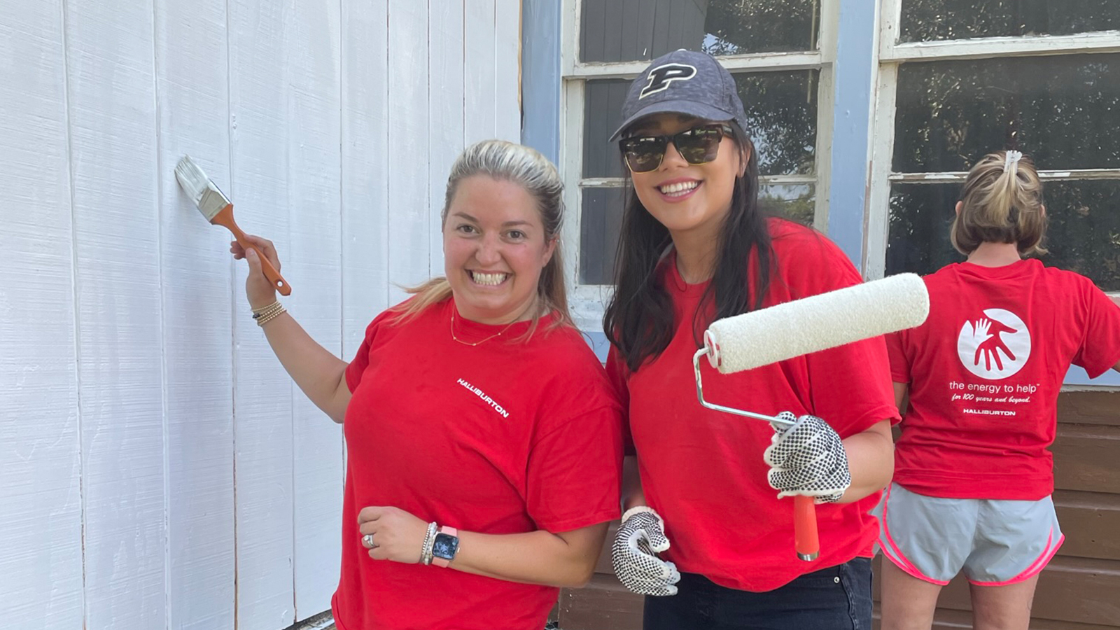 Halliburton volunteers painting the outside of a house.